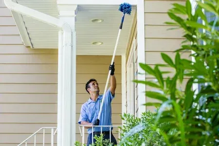 technician sweeping exterior house