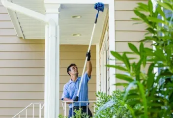 technician sweeping exterior house