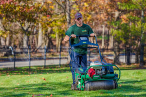 Dial Employee pushes lawn aeration machine across well-maintained lawn